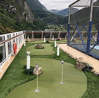 Adventure Golf & Sports miniature golf course on a cruise ship deck with mountains in the background