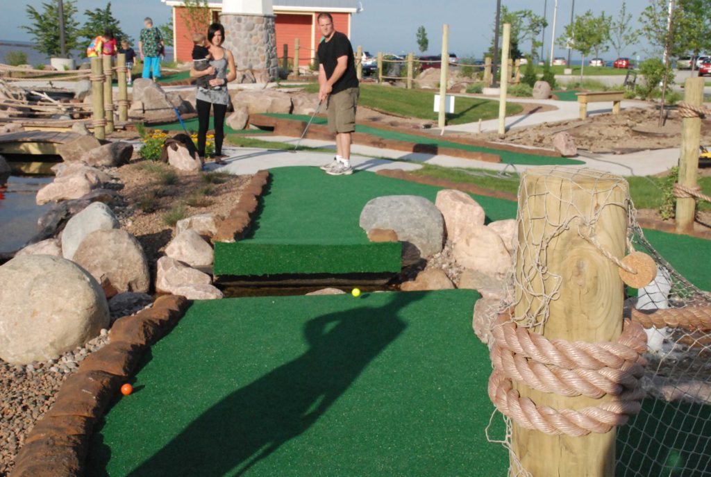 Couple playing mini golf on a sunny outdoor miniature golf course in Sheboygan Wisconsin