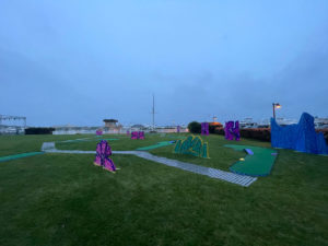Pulled back shot of portable mini golf course showcasing the multiple theme elements and the walkway winding from hole to hole at the AMEX Event in Montauk, NY.