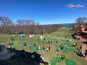 Outdoor, high-angled image of portable mini golf course at Vanderbilt Museum being played on by friends and families of various ages.