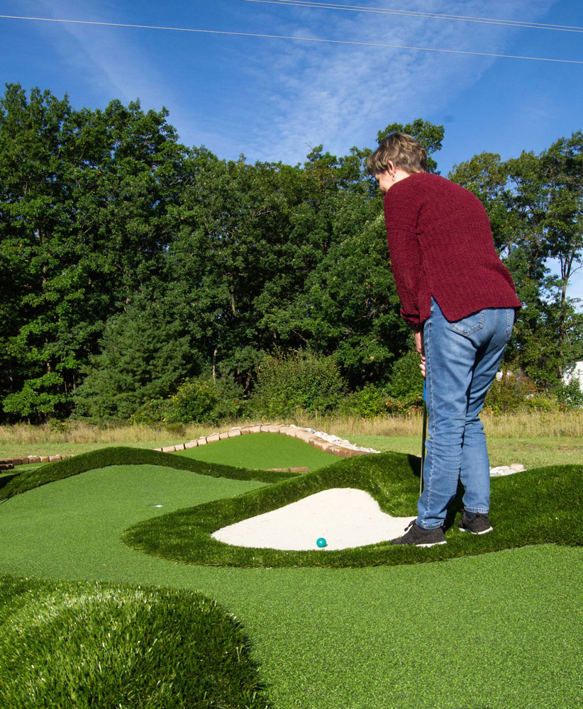 Player watches her putt along a natural-looking AGS Bunkers & Bumps™ miniaturized golf fairway
