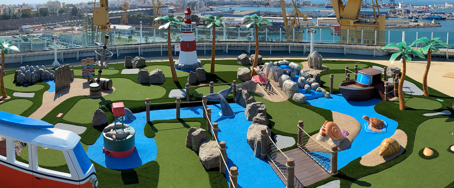 Overhead image of mini golf course on RCL Liberty Cruise Ship’s deck including multiple obstacles and nautical theme with Cadiz, Spain in the background.
