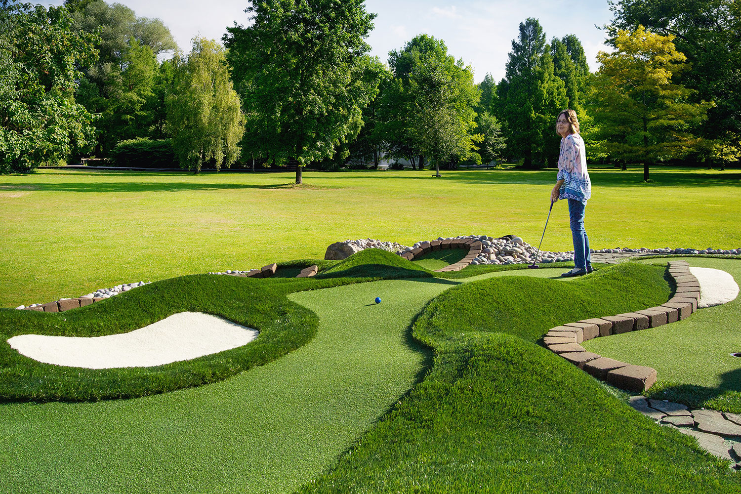 Player watches her putt along a natural-looking AGS Bunkers & Bumps™ miniaturized golf fairway