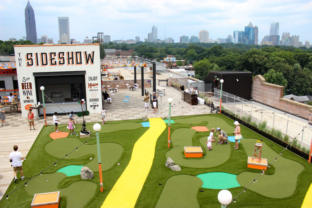People playing miniature golf on Ponce City Market rooftop. Skyline of Atlanta in the background.