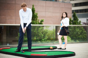 A GWU alumnus ready to putt on the MiniLinks™ Jr. miniature golf course as an alumna looks on.