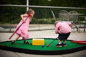Young girl and boy mini golf players trying to find a putt trapped inside a MiniLinks™ Jr. obstacle.