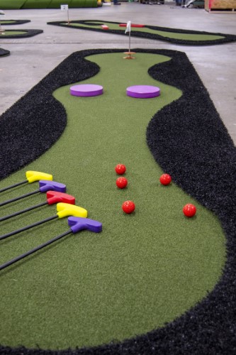 4 putters and 4 golf balls laid out on a RollOut golf hole