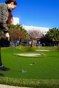 Woman’s putt on a Throttle & Swing mini golf hole designed by AGS ends up inches past the hole