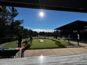 Strings of lights above the mini golf course at Northern Lights FEC illuminate the course for dusk / nighttime play