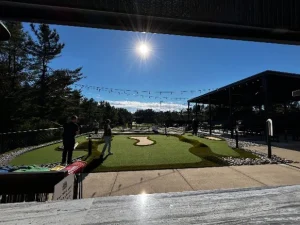 Strings of lights above the mini golf course at Northern Lights FEC illuminate the course for dusk / nighttime play